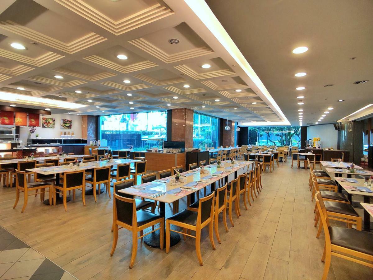 Evergreen Laurel Hotel - Taichung Exterior foto The photo shows the interior of a restaurant. It features a spacious dining area with several wooden tables and chairs arranged in rows. The floor has a light wood finish, complementing the stylish design. The ceiling is decorated with a modern patte